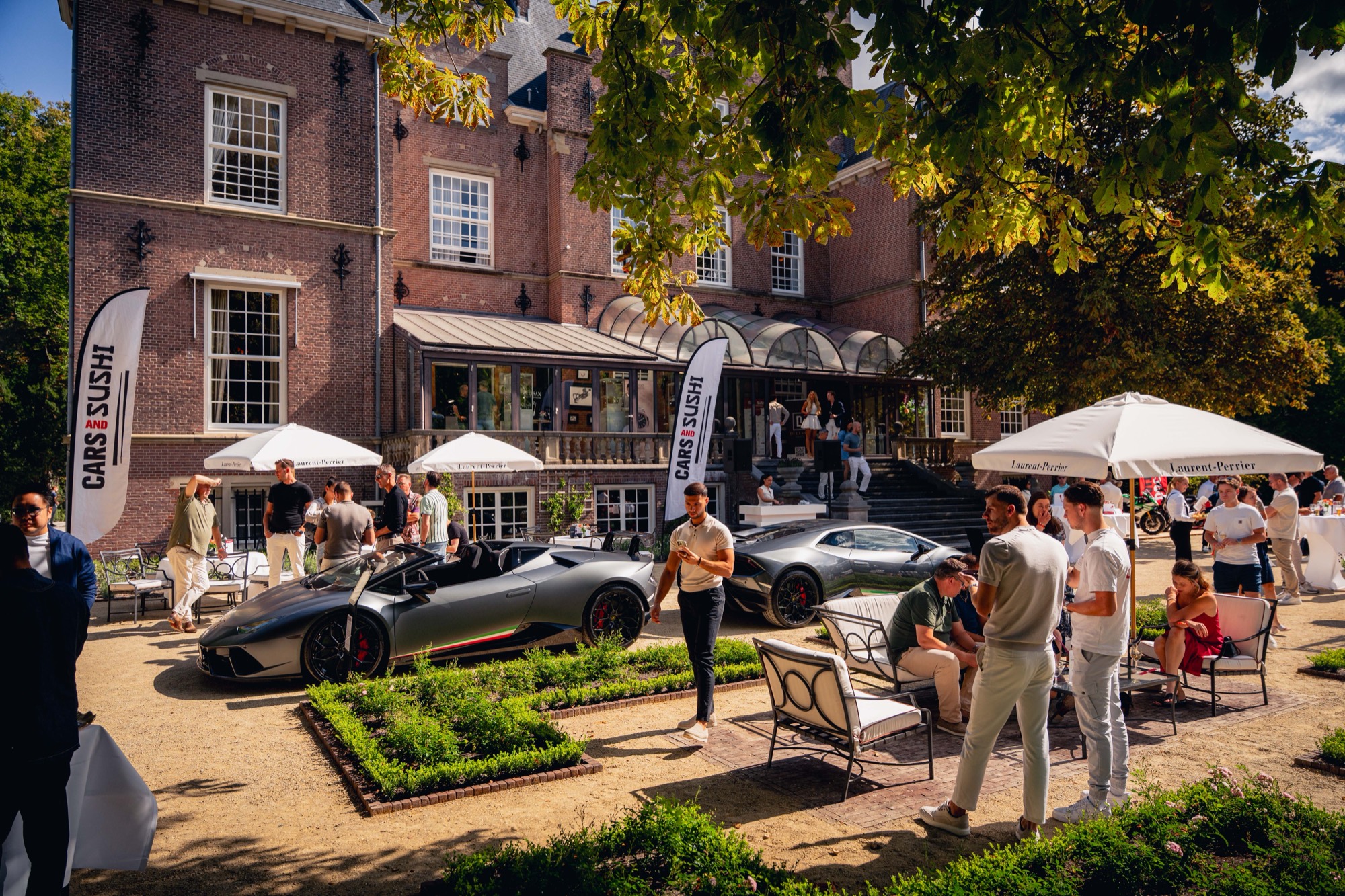 Supercars voor een landhuis tijdens een Cars & Sushi-avond.